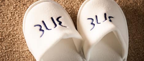 A pair of white slippers with embroidered text on the top.