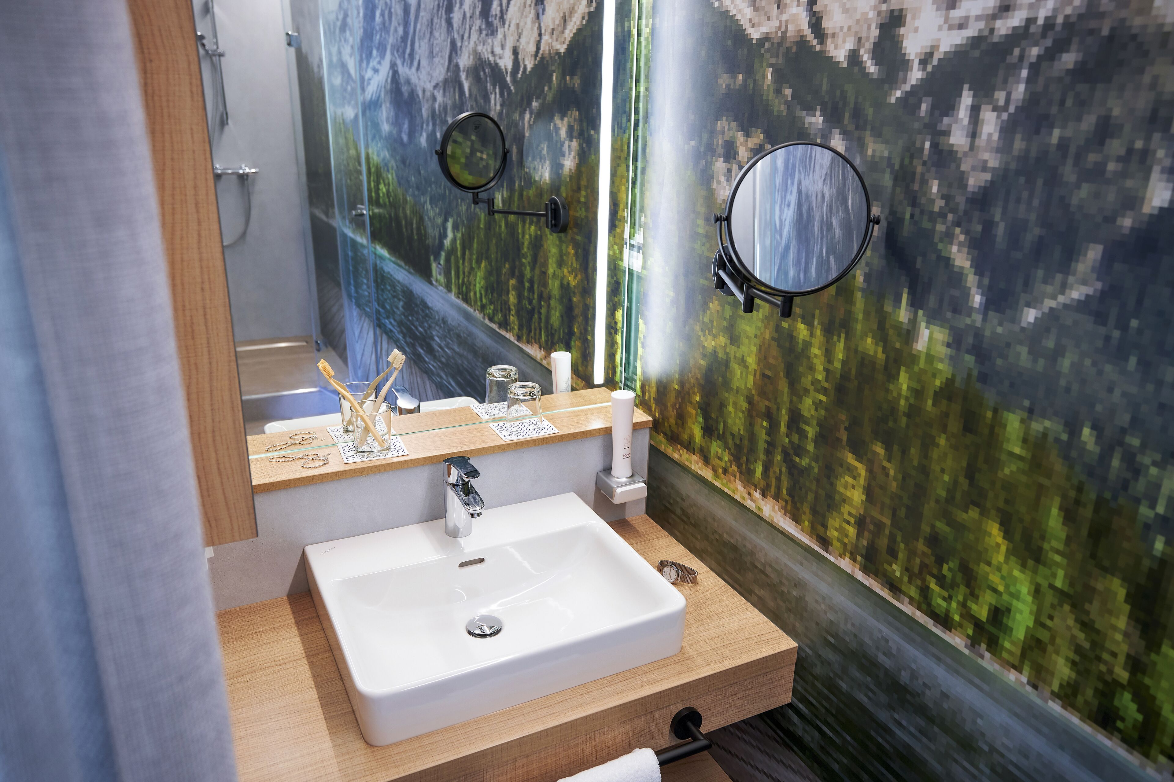 A bathroom with a white sink, wooden vanity, and a mirror.