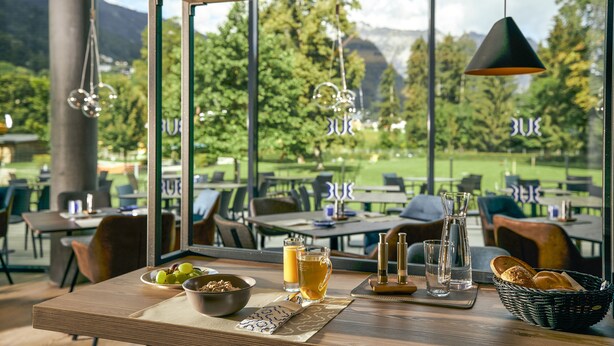 A dining area with a table set for two, a bowl of fruit, a pitcher, and a basket of bread. - TUI BLUE Montafon (Tschagguns)