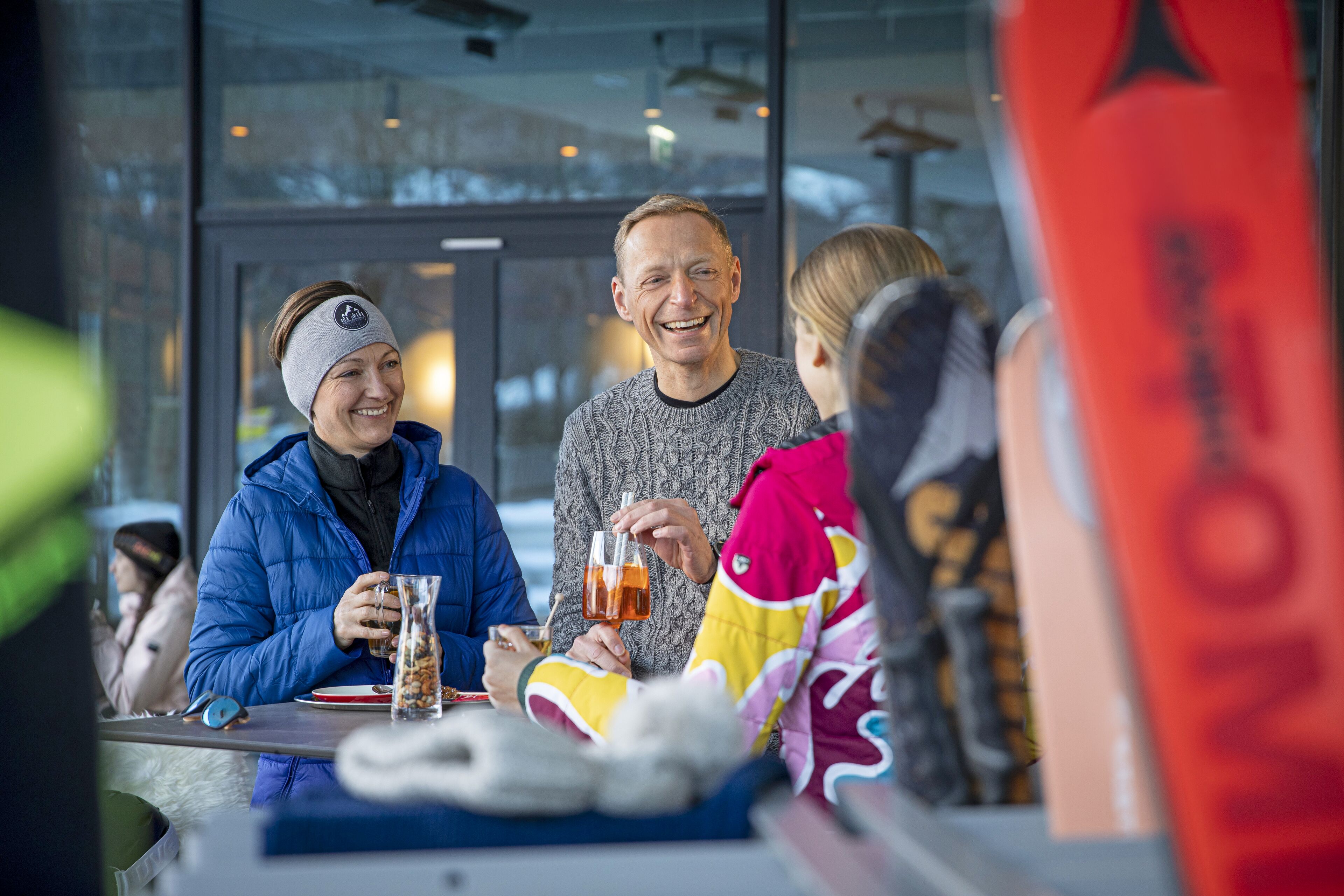 Eine Gruppe von Menschen sitzt an einem Tisch in einem Restaurant, vor ihnen steht ein Getränk.