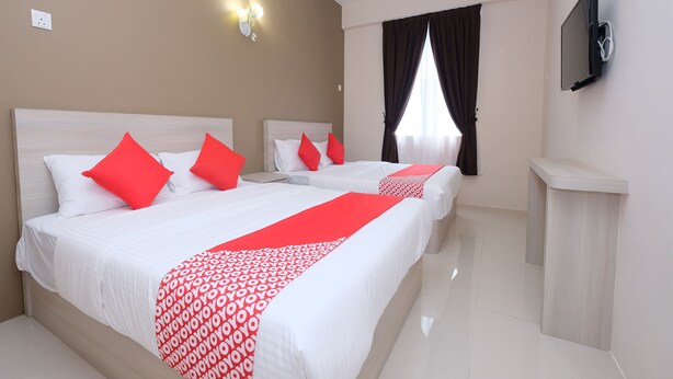 A hotel room with two beds, red pillows, a red and white patterned bed runner, a flat-screen TV mounted on the wall, and a window with dark curtains. - Mancalin Hotel (Kuantan)