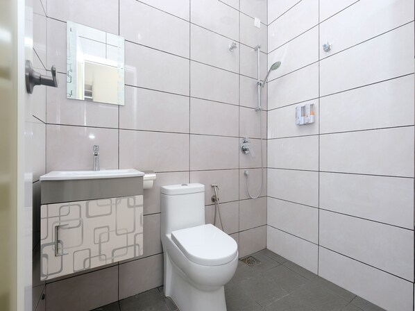 Une salle de bain moderne équipée de toilettes, d’un lavabo et d’une douche.
