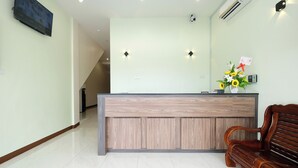 A reception area with a wooden reception desk, a bench, a wall-mounted TV, and a wall-mounted air conditioner. - Mancalin Hotel (Kuantan)