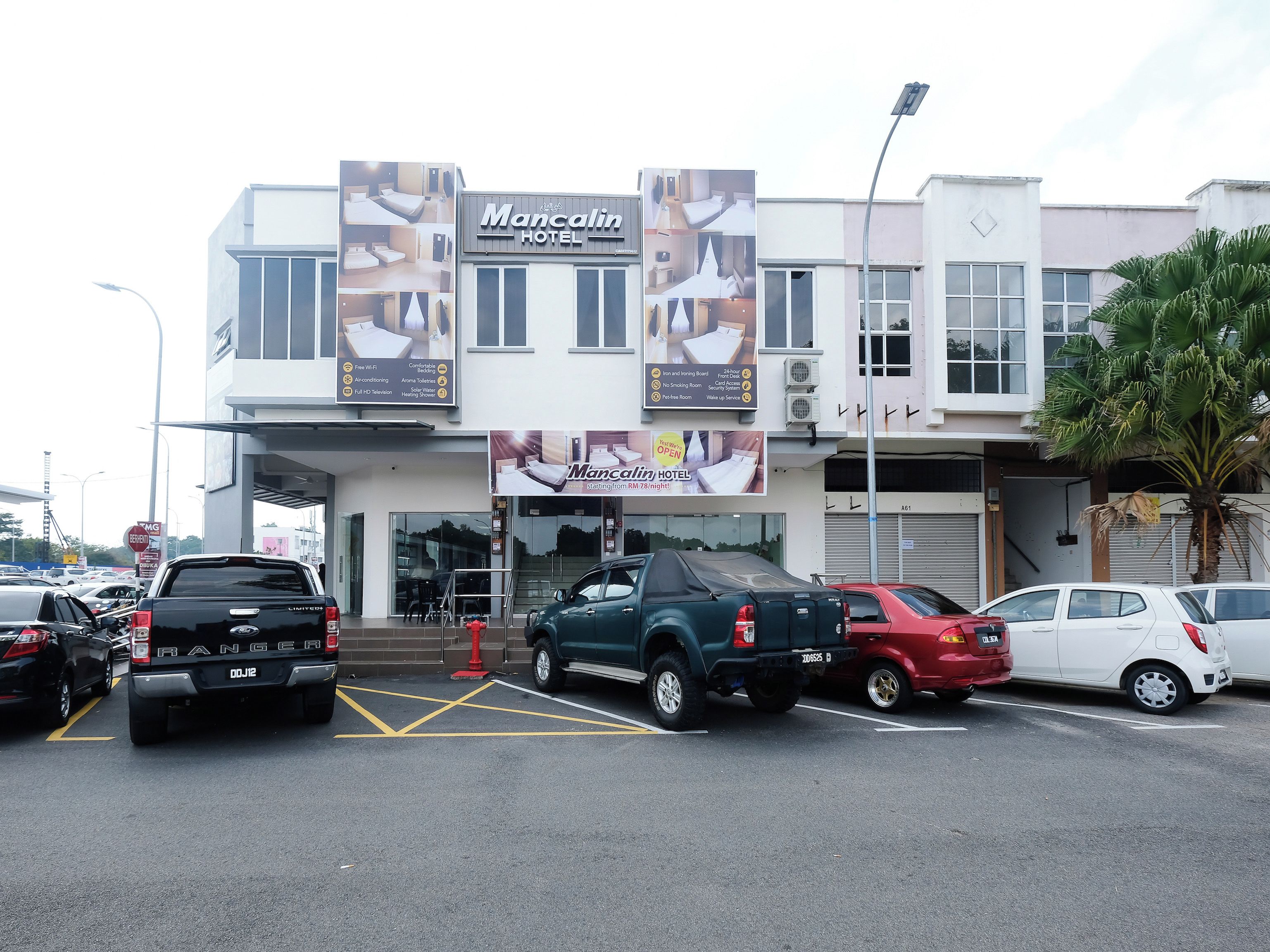 A hotel with a signboard advertising amenities like free WiFi, comfortable bedding, and a 24-hour room service.