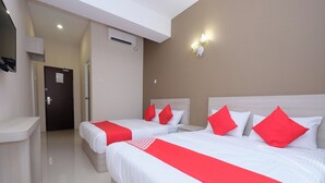 A hotel room with two beds, each with white bedding and red accents, a desk, a door, and an air conditioning unit. - Mancalin Hotel (Kuantan)