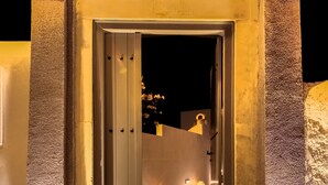 A stone entrance with a door, illuminated by lights on either side. - Pasithea Luxury Suites (Santorini)