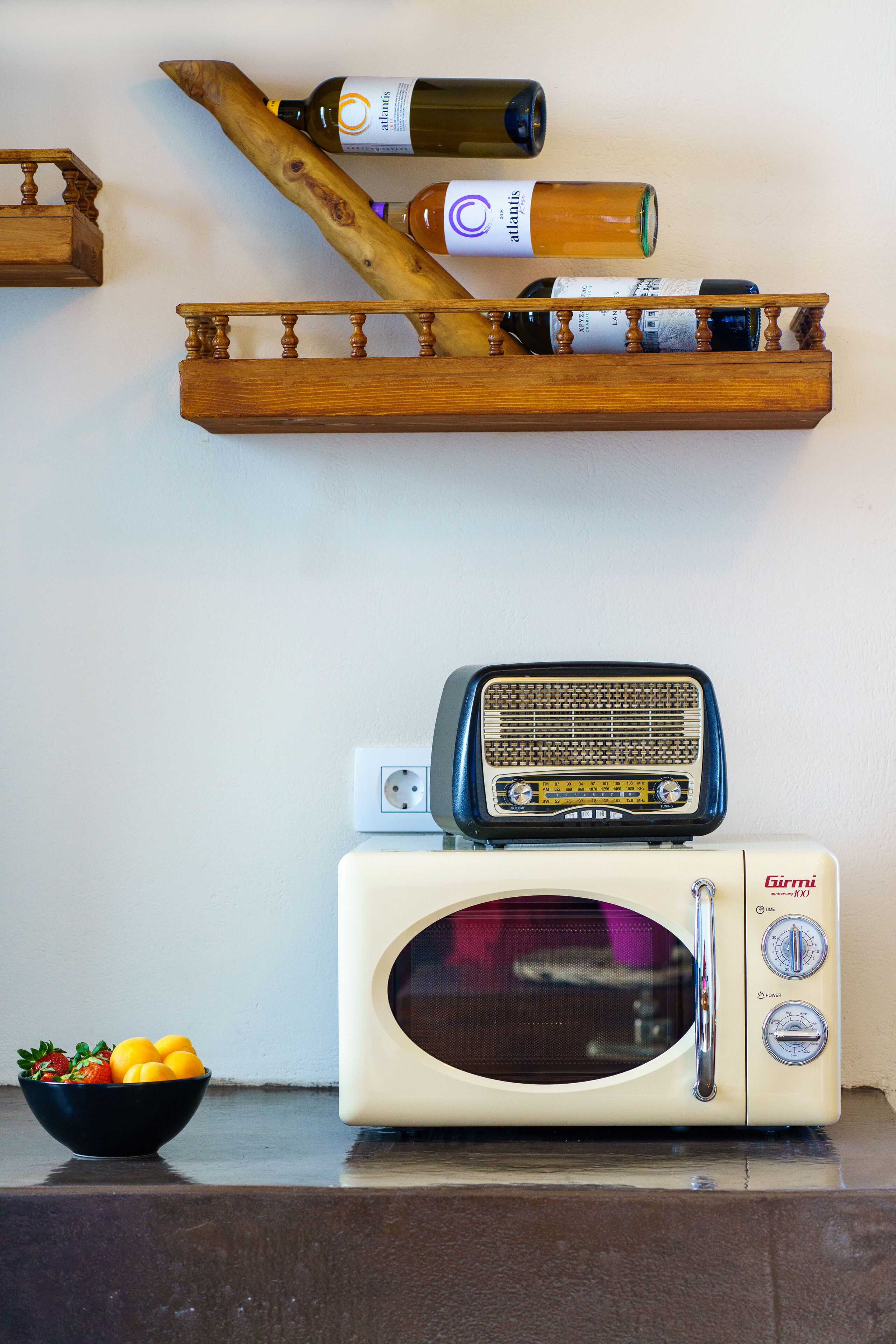 Une cuisine équipée d’un four à micro-ondes, d’une radio et d’un saladier rempli de fruits posé sur le comptoir.