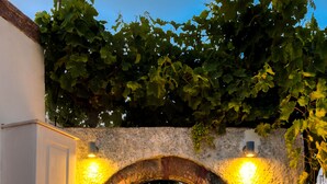 An arched doorway with stone walls and a white building. - Pasithea Luxury Suites (Santorini)