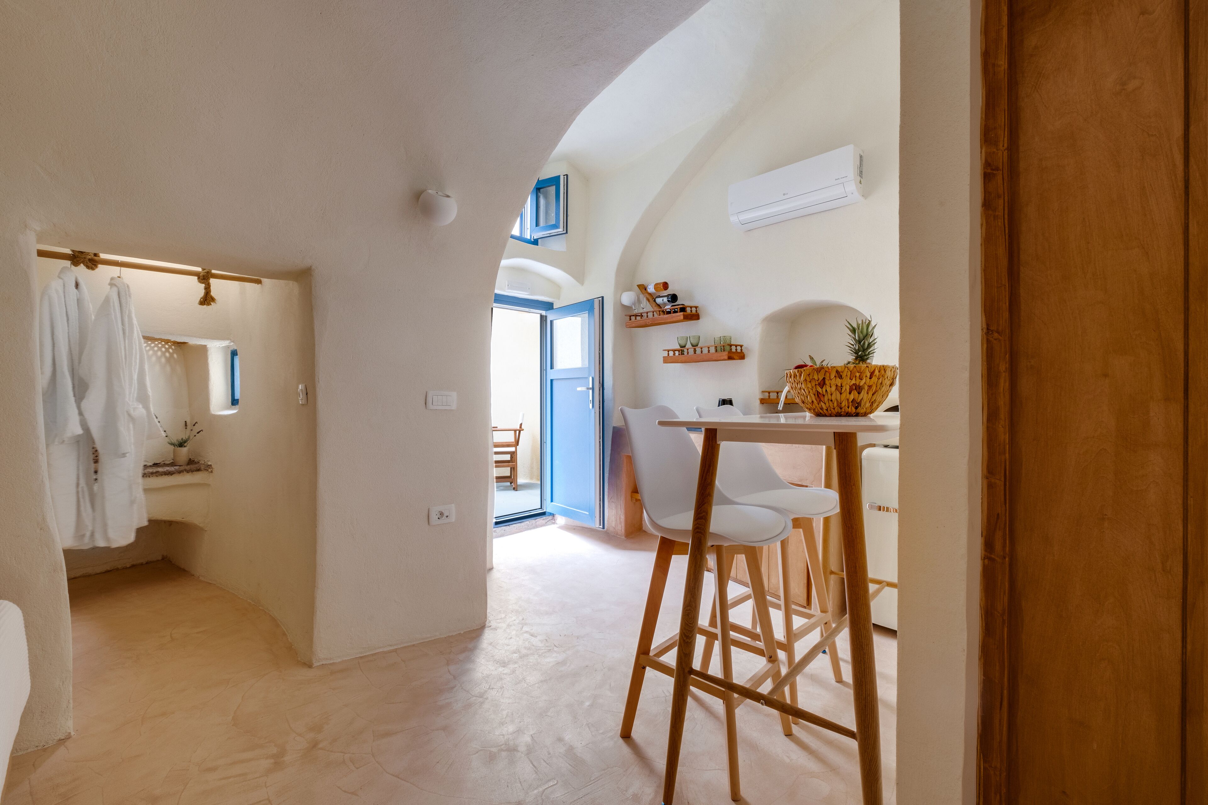 Una cocina moderna con taburetes blancos, una mesa de madera y una cesta de fruta.