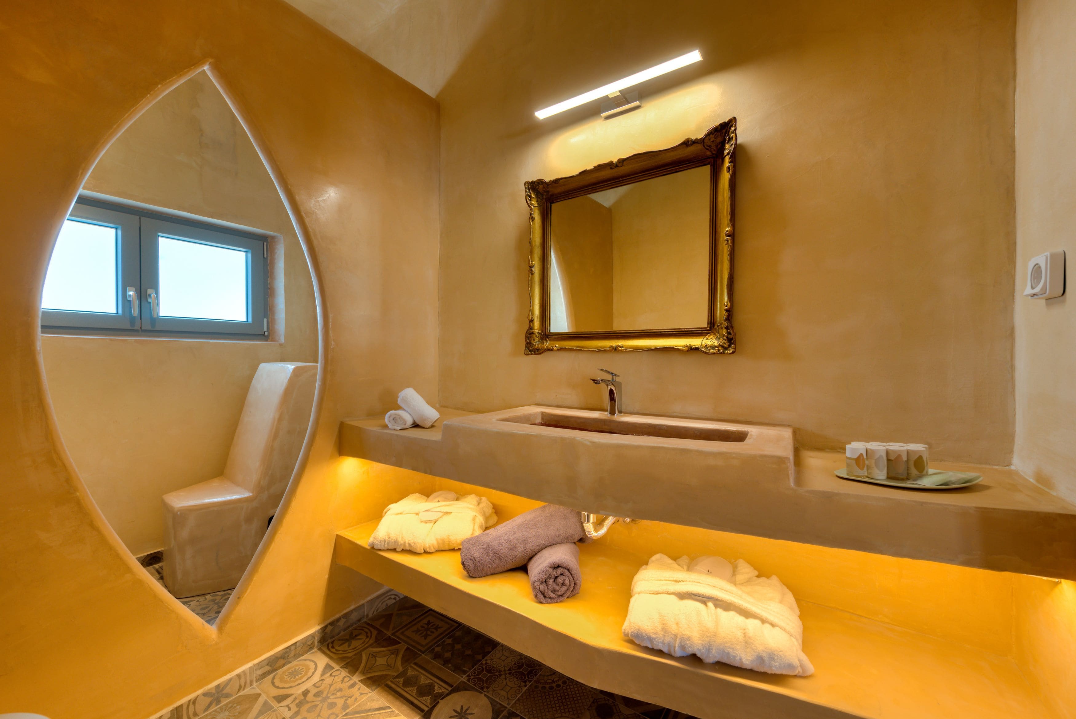 Une salle de bain avec un grand miroir, un lavabo et des serviettes posées sur un meuble.
