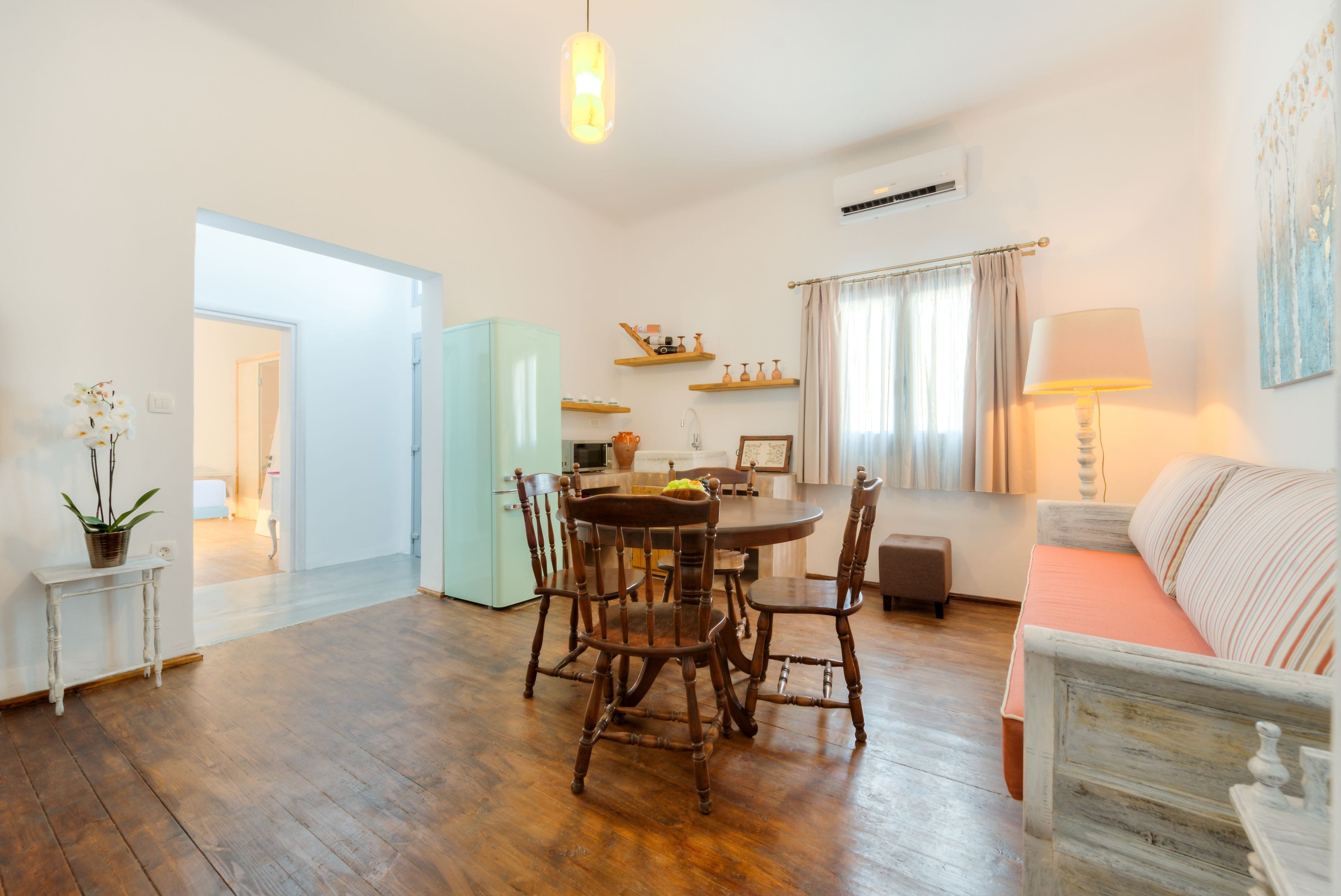 Un salón amplio con una mesa de comedor, sillas, un sofá y una lámpara.