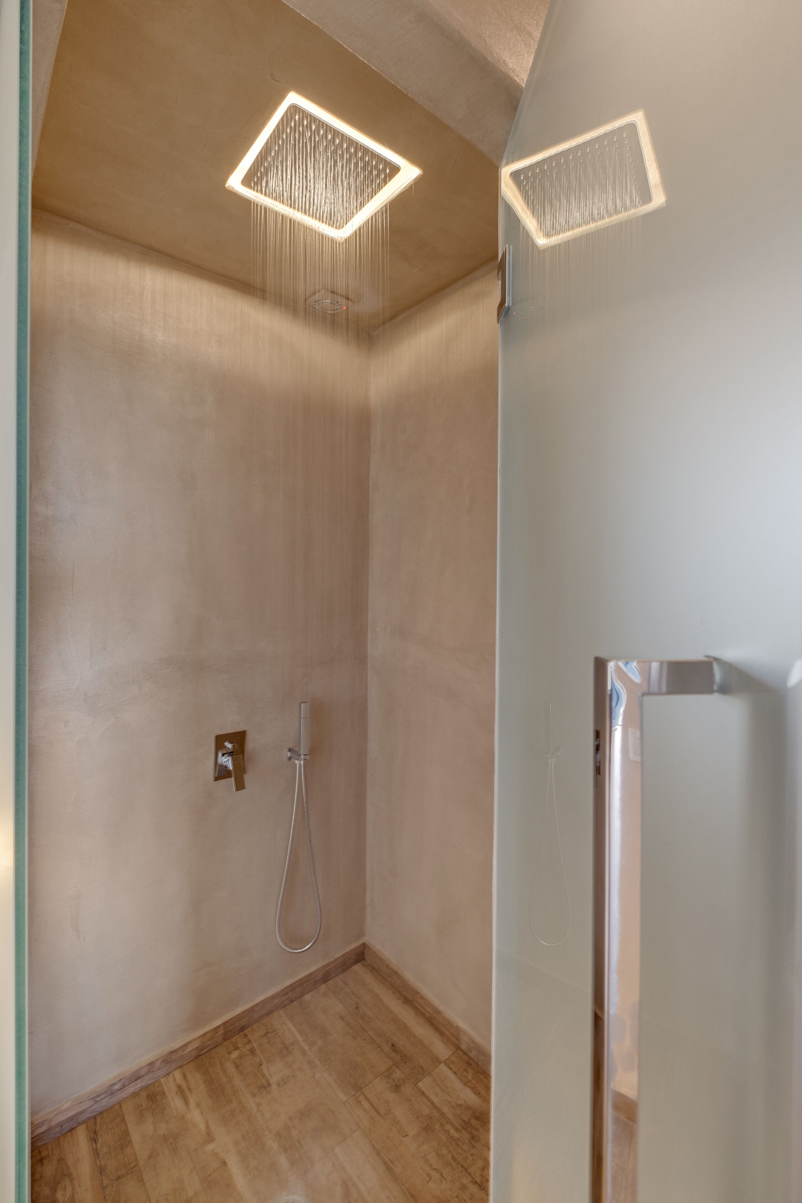 Un baño moderno con ducha, puerta de vidrio y una lámpara en el techo.