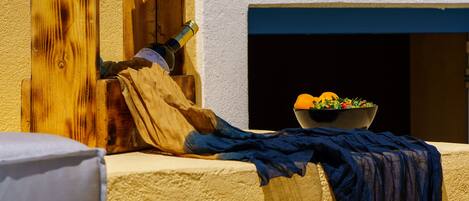 A poolside area with a wooden structure, a bowl of fruit, and a blue cloth draped over a ledge.