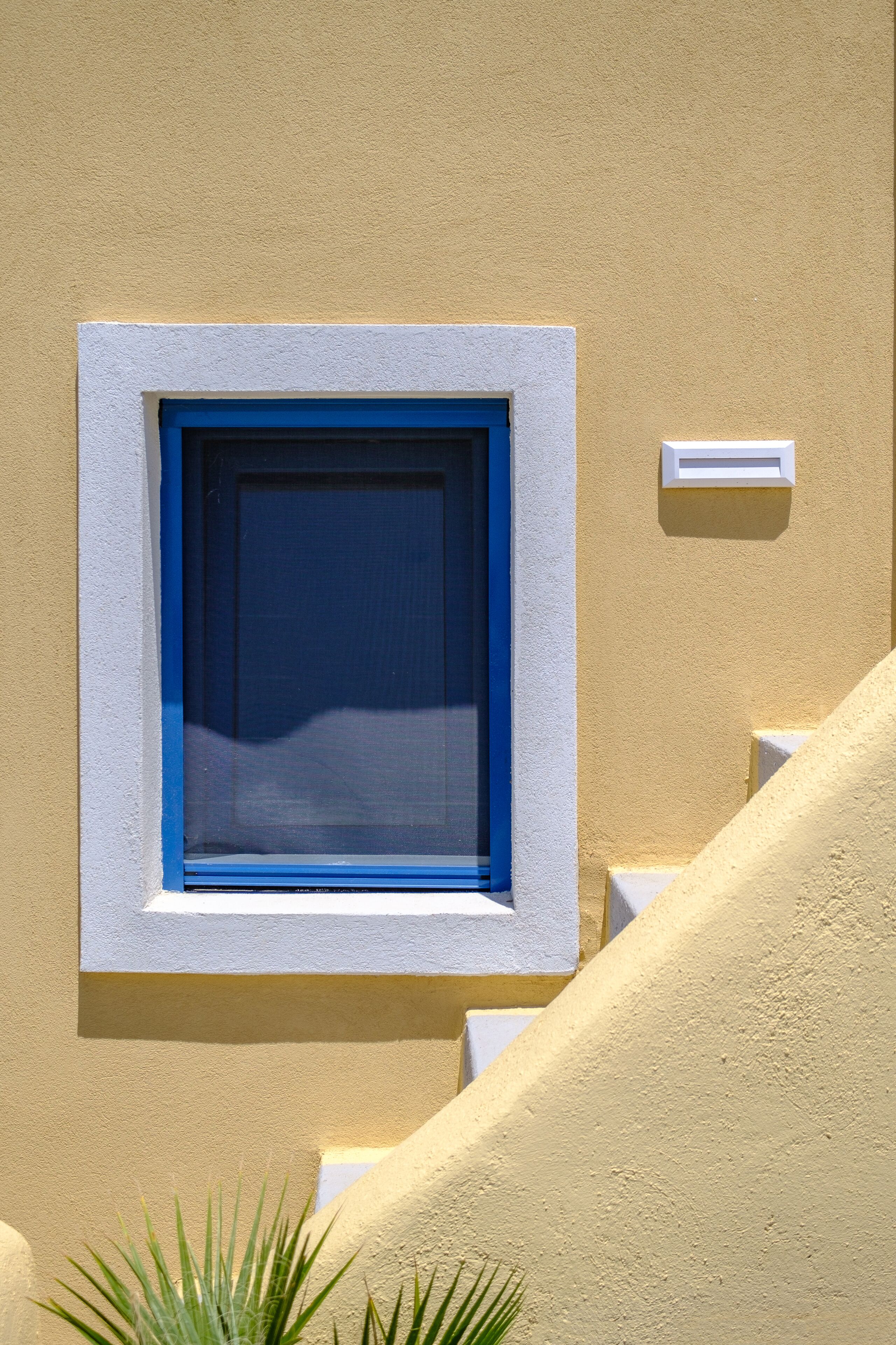 A window with a blue frame and a white wall.