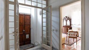 Una stanza con una porta in legno, una porta di vetro, una sveglia e una sedia.