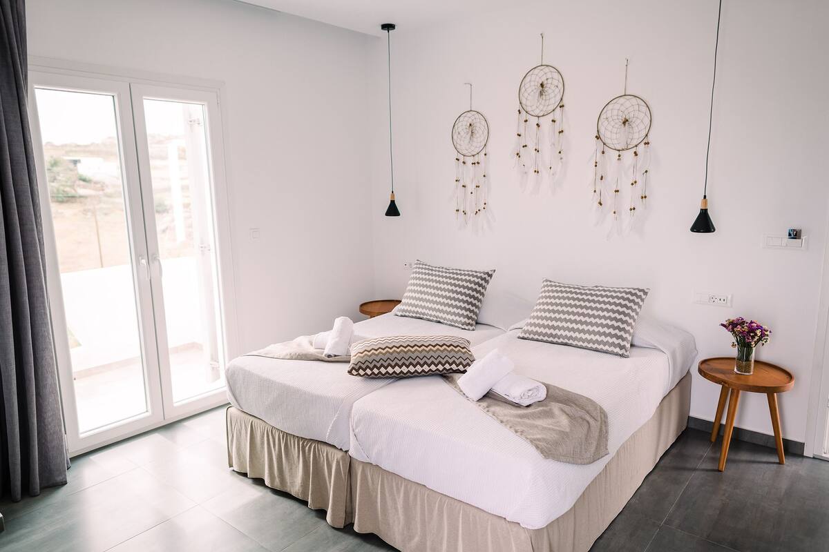 Quarto com cama, mesas de cabeceira, janela e decorações nas paredes.