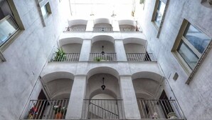 Un edificio de varios pisos con una escalera central, balcones con barandillas y una serie de ventanas.