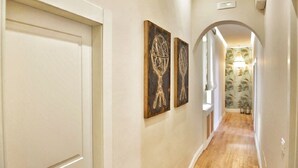 Un pasillo con piso de madera, paredes blancas y dos obras de arte colgadas en la pared.