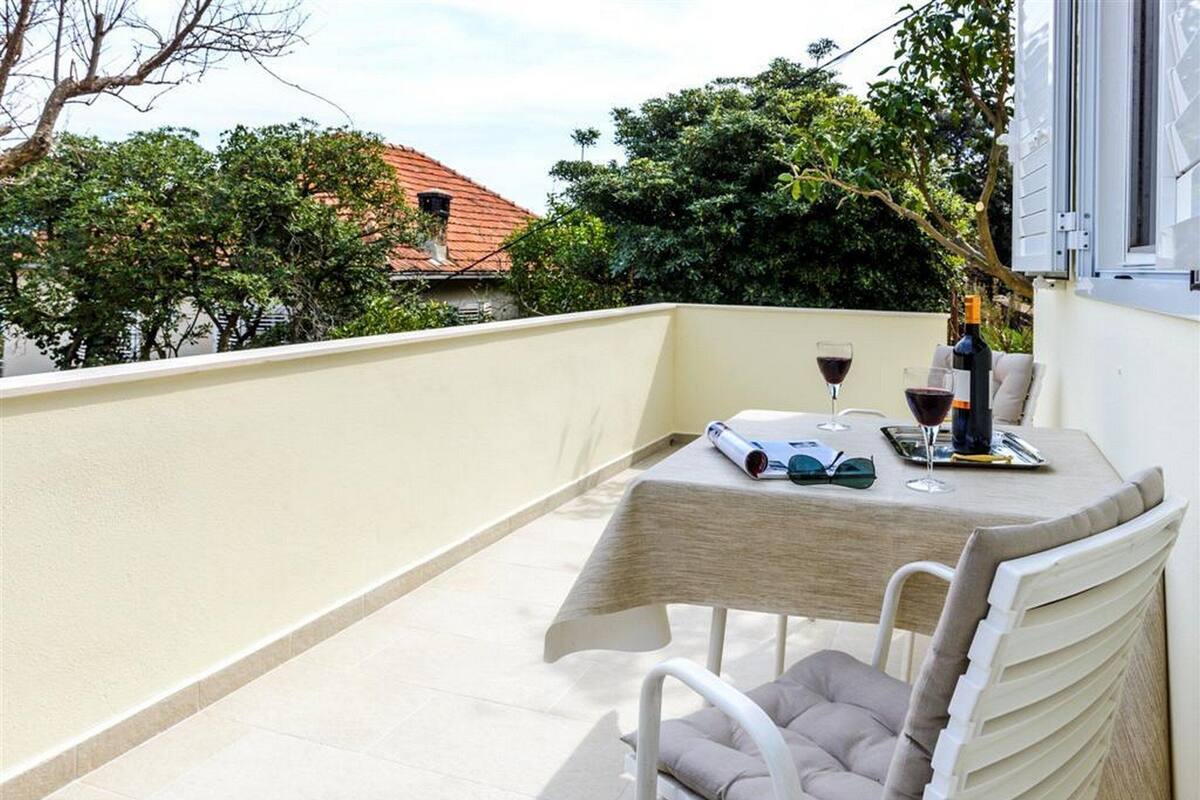 Ein Balkon mit Tisch für zwei Personen, einer Weinflasche und einem Buch.