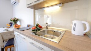 Eine moderne Küche mit Spüle aus Edelstahl, Arbeitsplatte aus Holz und weißen Schränken.