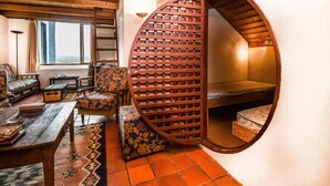 Ein gemütliches Zimmer mit einer runden Holzwand, einem Sofa, einem kleinen Tisch und Blick ins Freie.
