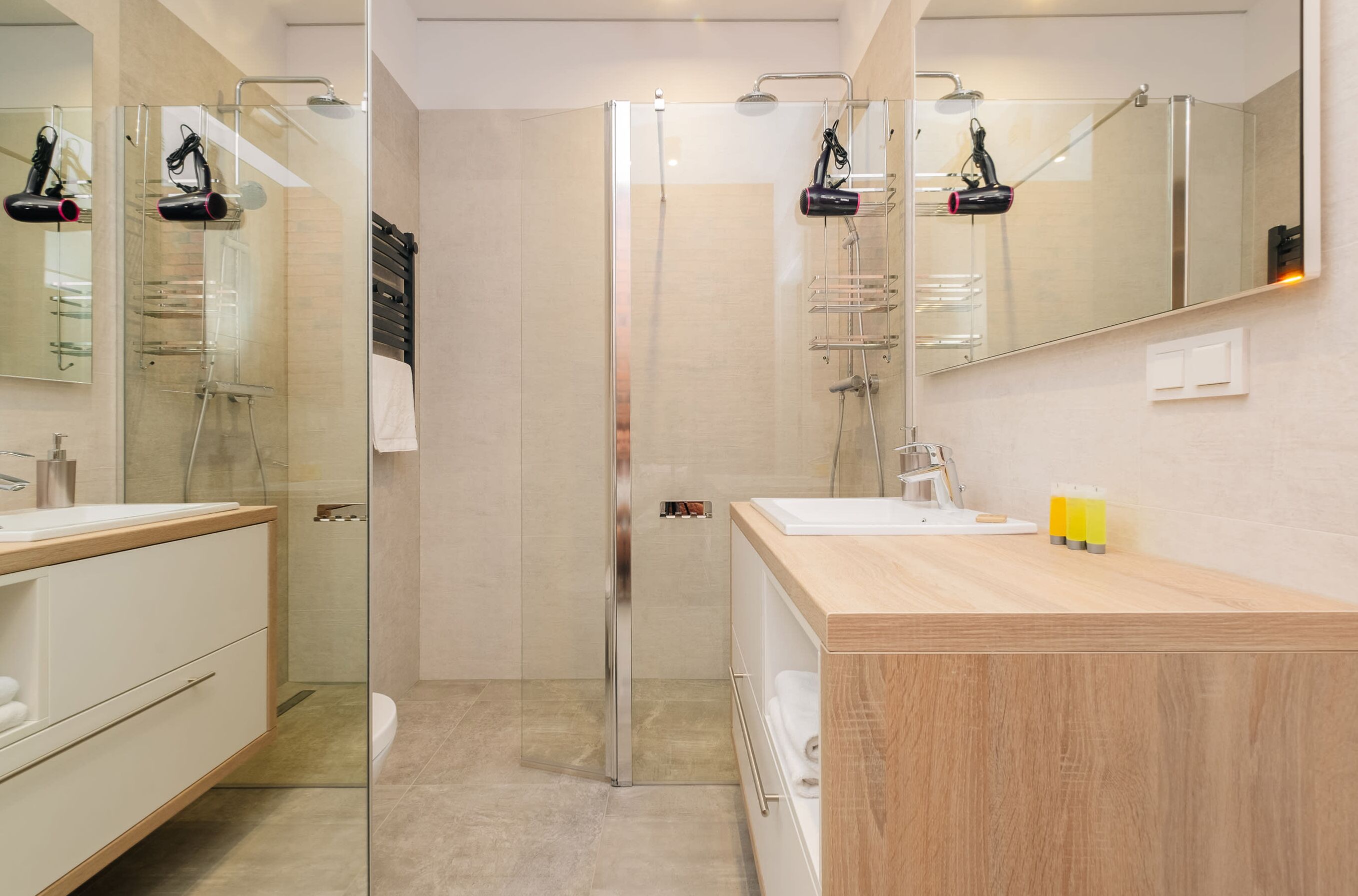 A modern bathroom with a glass-enclosed shower, a wooden vanity, and a large mirror.