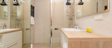 A modern bathroom with a glass-enclosed shower, a wooden vanity, and a large mirror.