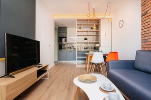 Ein modernes Wohnzimmer mit Flachbildfernseher, einer Couch und einem Essbereich mit Tisch und Stühlen.