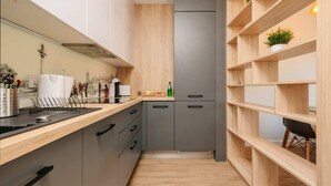 A modern kitchen with grey cabinets, a wooden countertop, and a built-in shelving unit with plants.