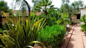 A garden pathway with various plants and a lamp post. - Villaggio Turistico Defensola (Vieste)