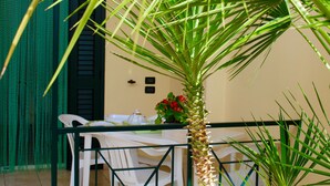 A table with chairs and a potted plant with red flowers. - Villaggio Turistico Defensola (Vieste)