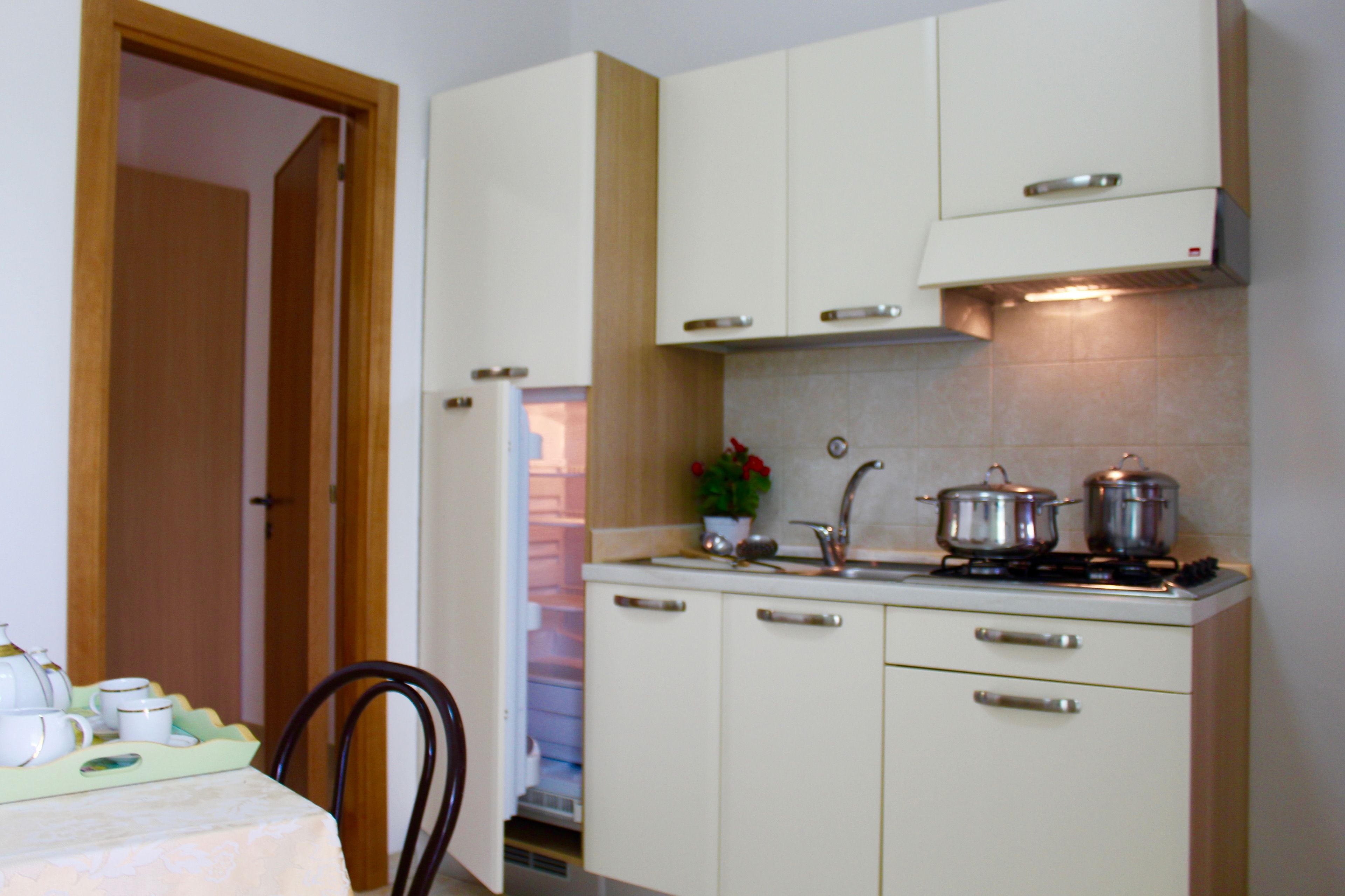 Una cocina compacta con armarios blancos, una estufa y un lavabo.