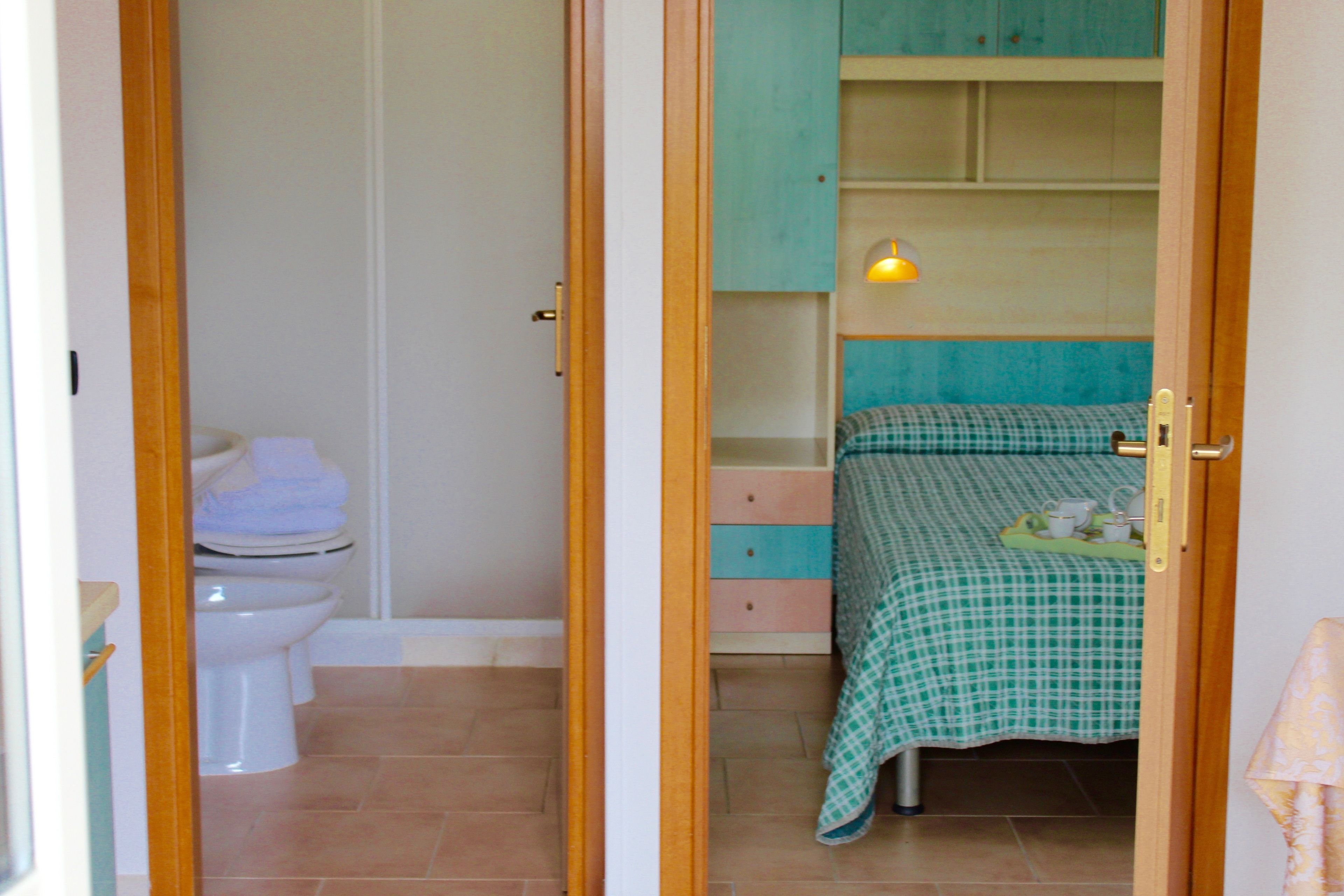 A bedroom with a bed, a bedside table, a lamp, and a wardrobe.