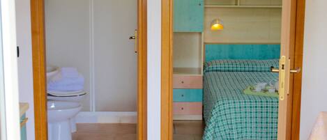 A bedroom with a bed, a bedside table, a lamp, and a wardrobe.