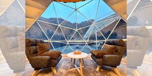 A geodesic dome room with two armchairs, a small round table, and a view of mountains through a large window. - Koshikano Onsen (Kirishima)