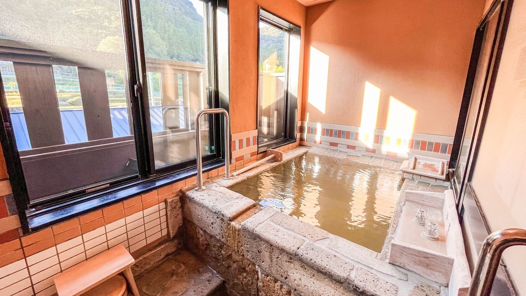 A hot spring bath with a bench, a small sink, and a window with a view of the outdoors.