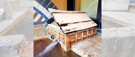 A wooden structure with a metal pipe discharging water into a pool.