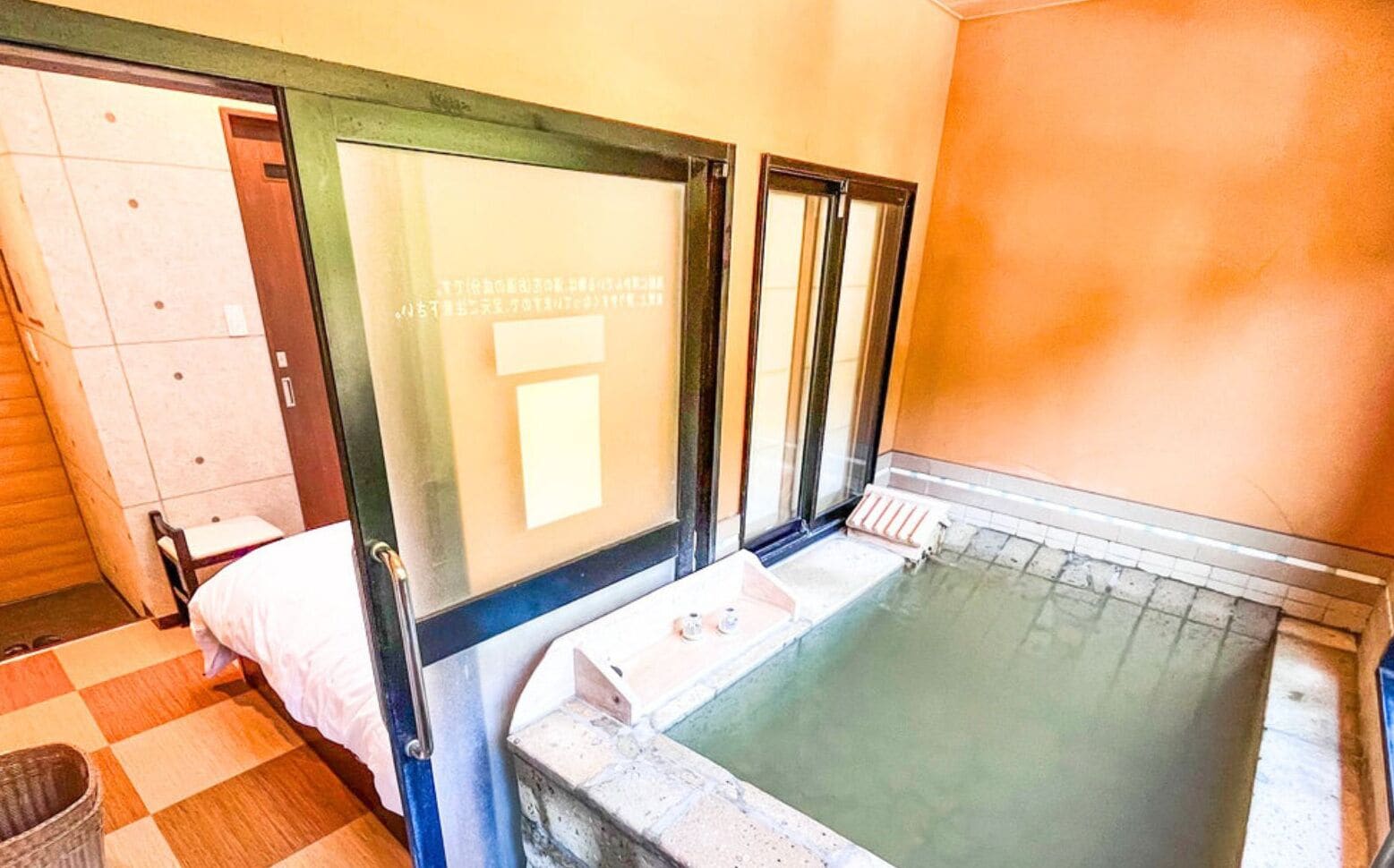 A room with a stone bathtub, a wooden bench, and a door with frosted glass panels.