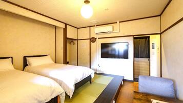 A hotel room with two beds, a TV, a wooden table, and a chair.