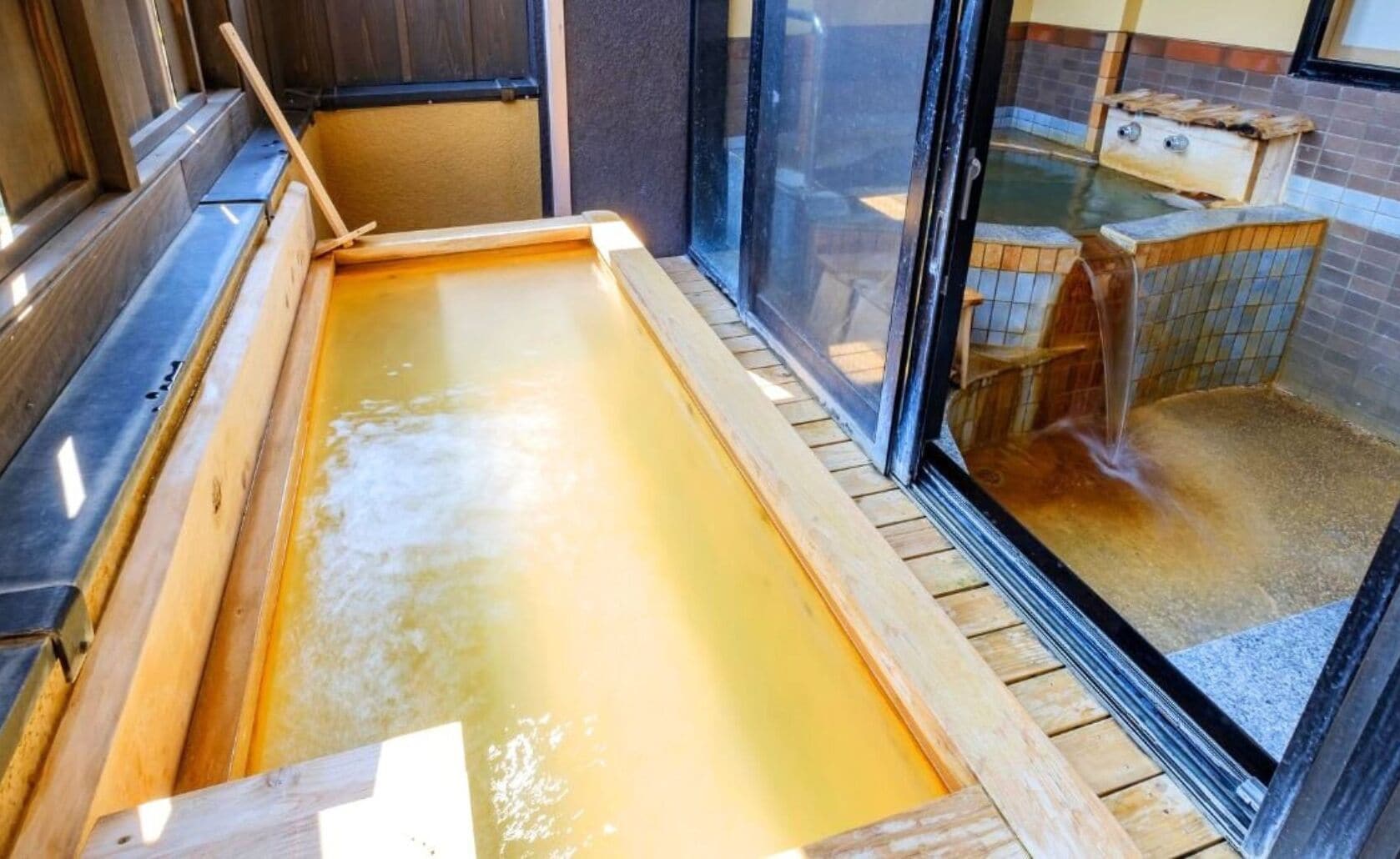 Una tradizionale onsen giapponese con una vasca in legno per immergersi e una piccola panca di legno.