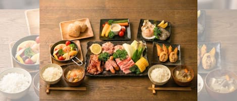 A wooden table with various dishes including sushi, sashimi, and rice bowls.
