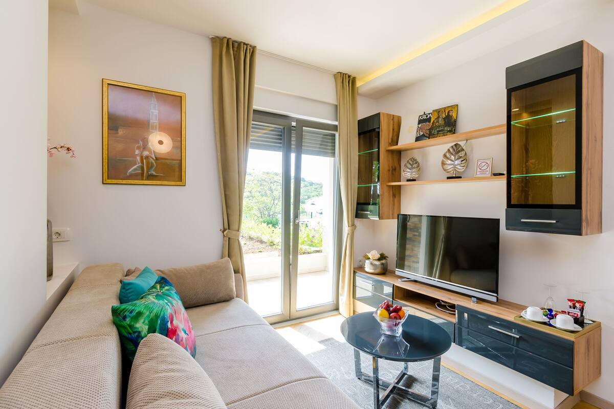 Un salon moderne comprenant un canapé, un téléviseur à écran plat, une table basse et une porte-fenêtre coulissante donnant sur un espace extérieur.