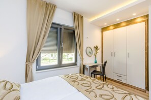 Ein Schlafzimmer mit Bett, Schreibtisch, Stuhl, Kleiderschrank und einem Fenster mit Vorhängen.