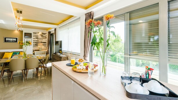 A modern kitchen with a dining area, large windows, and a view of greenery. - Villa Dolores Apartments  (Dubrovnik)