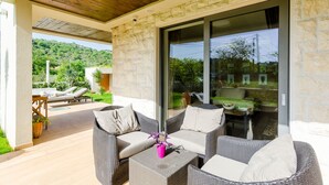 A covered outdoor seating area with wicker furniture and a glass door leading to a patio. - Villa Dolores Apartments  (Dubrovnik)