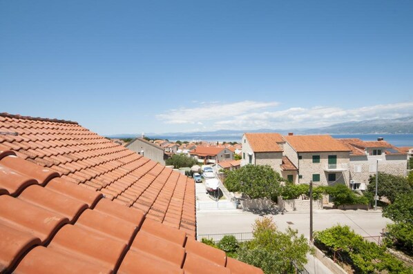 A coastal residential area with terracotta-tiled roofs, stone buildings, and a clear view of the sea. - Apartments Jasenka Supetar (Supetar)