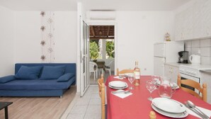 Ett kompakt bostadsutrymme med en matplats, ett litet kök och en blå soffa.