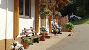 Rakennuksessa on kyltti, jossa lukee ”Gasthaus Pension Zum Spälarwald”, ja sen ulkopuolella on puinen penkki.