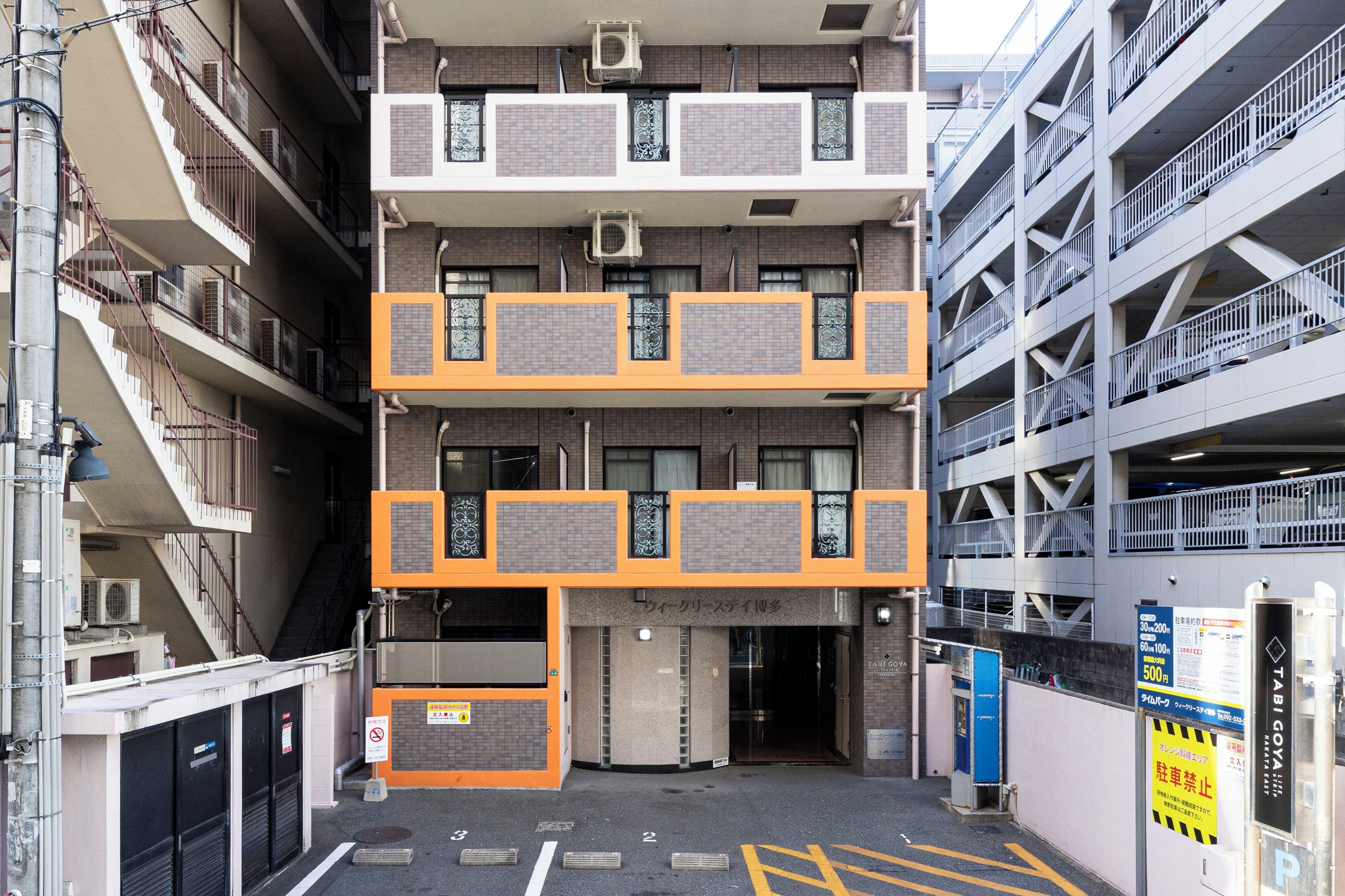 Un immeuble à plusieurs étages doté d’une entrée au niveau du sol, d’un espace de stationnement couvert et d’un escalier menant aux étages supérieurs.
