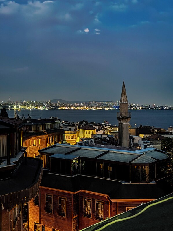 A coastal cityscape at dusk with traditional buildings and a prominent tower. - The New Season Apart (Istanbul)
